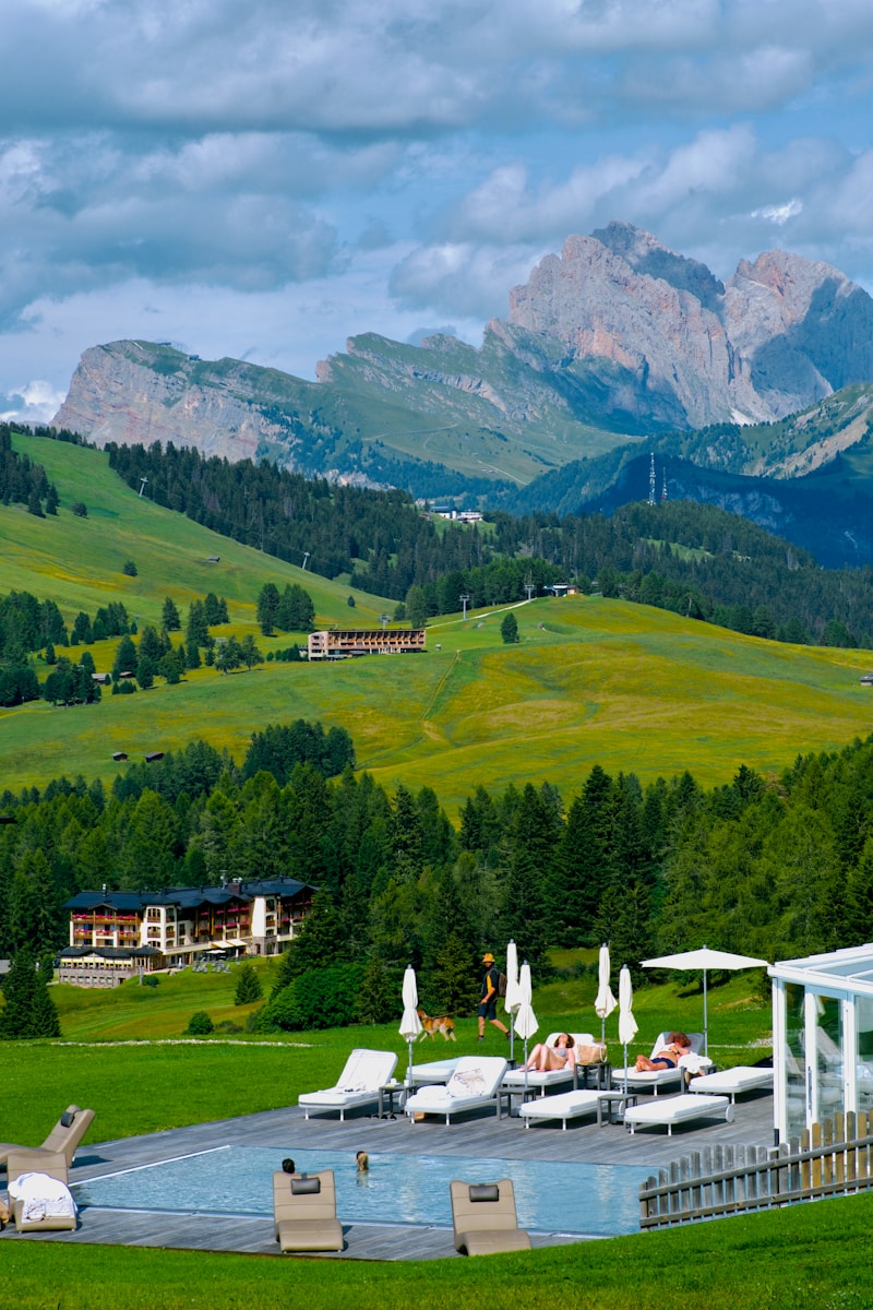 A pool surrounded by lounge chairs in the middle of a lush green field